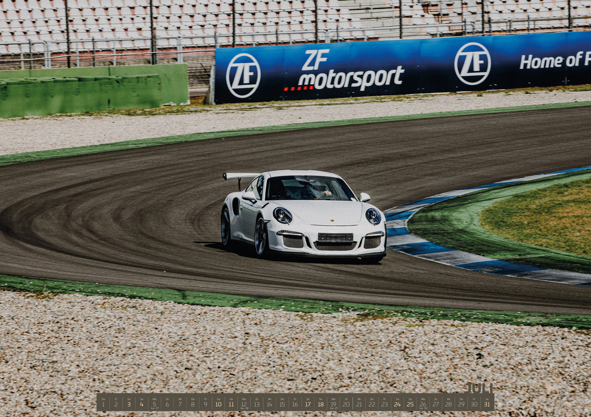 Trackday Kalender 2027 – Juli: Ein weißer GT-Rennwagen fährt durch eine Rennstreckenkurve; Randsteine, Reifenabrieb und leichter Schräglauf vermitteln Dynamik