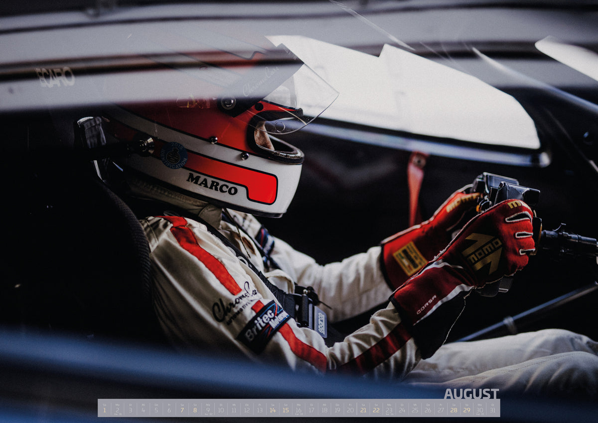 Trackday Kalender 2027 – August: Die enge Cockpitaufnahme zeigt behandschuhte Hände am Lenkrad und einen Teil des Rennanzugs; Fahrzeug und Fahrer verschmelzen zur Bewegung