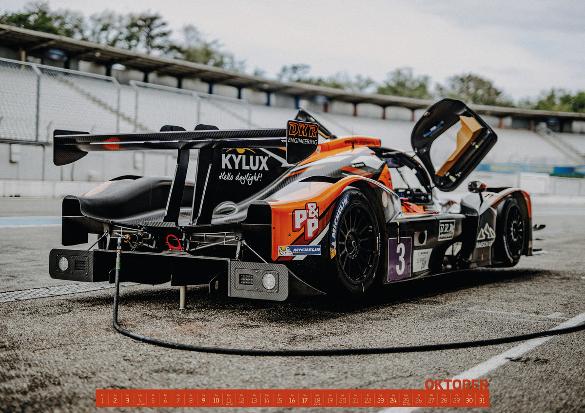 Trackday Kalender 2027 – Oktober: Ein flacher Rennprototyp steht von hinten in der Boxengasse; geöffnete Karosserieteile, großer Heckflügel und technische Details sind sichtbar