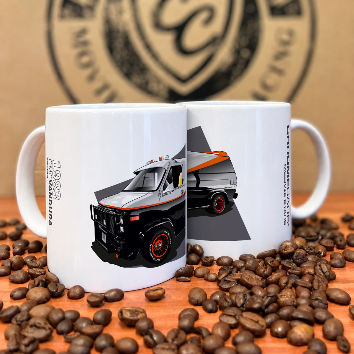 Zwei weiße Tassen mit schwarz-grauem GMC-Vandura-Motiv zwischen Kaffeebohnen.