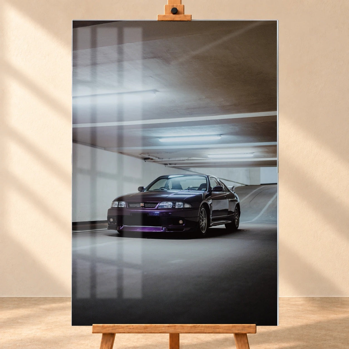Frontal dargestelltes Acrylglas-Wandbild im Hochformat als Visualisierung auf einer Holzstaffelei. Über dem Motiv eines dunkelvioletten Nissan Skyline GT-R R33 in einer Tiefgarage sind Fensterreflexionen zu sehen.