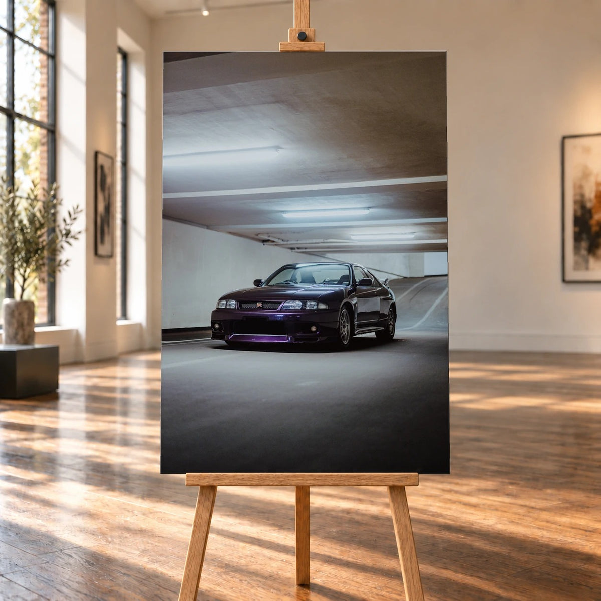 Raumvisualisierung mit einem hochformatigen Leinwandbild auf einer Holzstaffelei in einer sonnigen Galerie mit Holzfußboden. Auf dem Bild steht ein dunkelvioletter Nissan Skyline GT-R R33 in Dreiviertelansicht von vorn in einer Tiefgarage.
