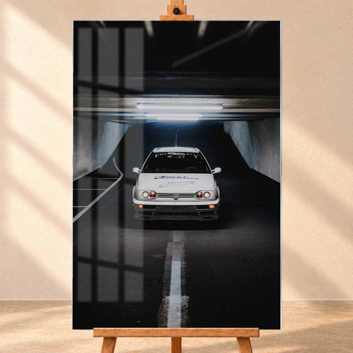 Frontal dargestelltes Acrylglas-Mockup im Hochformat auf einer Holzstaffelei vor heller Wand. Fensterspiegelungen überlagern das Motiv von Jesses weißem VW Jetta aus „The Fast and the Furious“, der mittig in einer dunklen Tiefgarage steht.