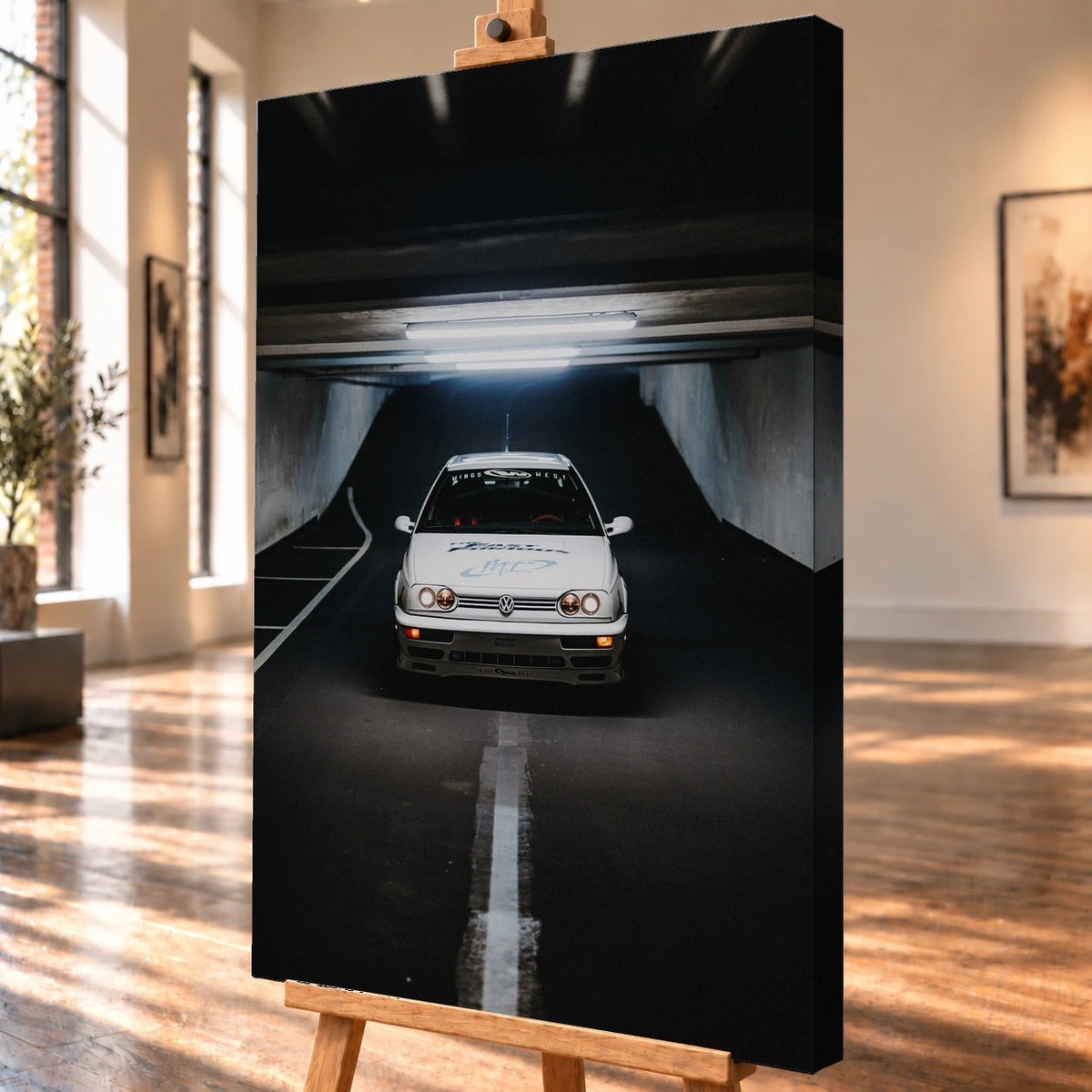 Schrägansicht eines visualisierten Leinwandbilds auf einer Holzstaffelei mit deutlich sichtbarer rechter Seitenkante. Auf dem Bild steht Jesses weißer VW Jetta frontal in einer dunklen Tiefgarage; eine weiße Bodenlinie führt auf den Wagen zu.