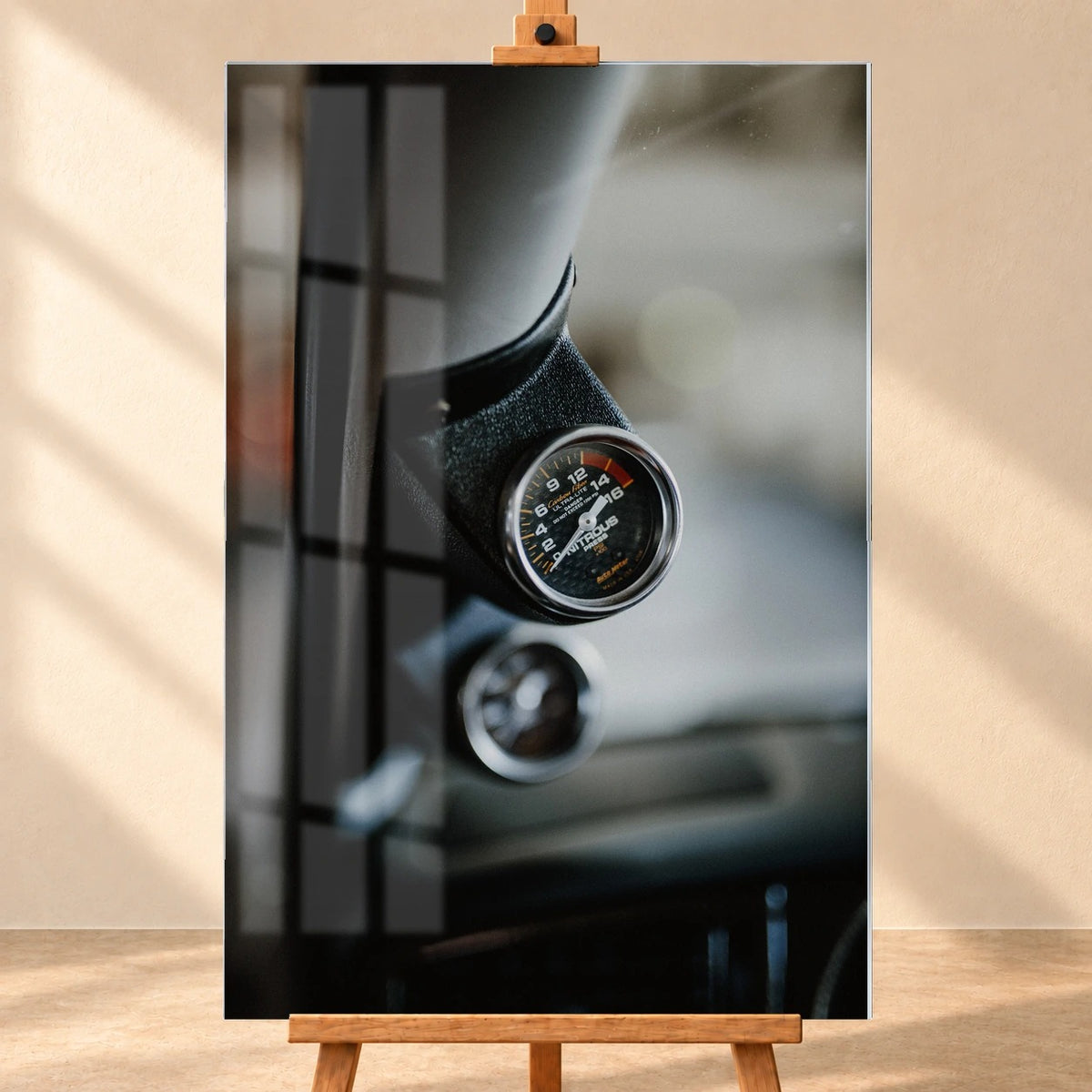 Frontale Visualisierung eines Acrylglas-Wandbilds im Hochformat auf einer Holzstaffelei vor heller Wand. Das Motiv zeigt die Lachgas-Druckanzeige in Jesse’s VW Jetta; über der linken Bildhälfte ist eine Fensterspiegelung dargestellt.