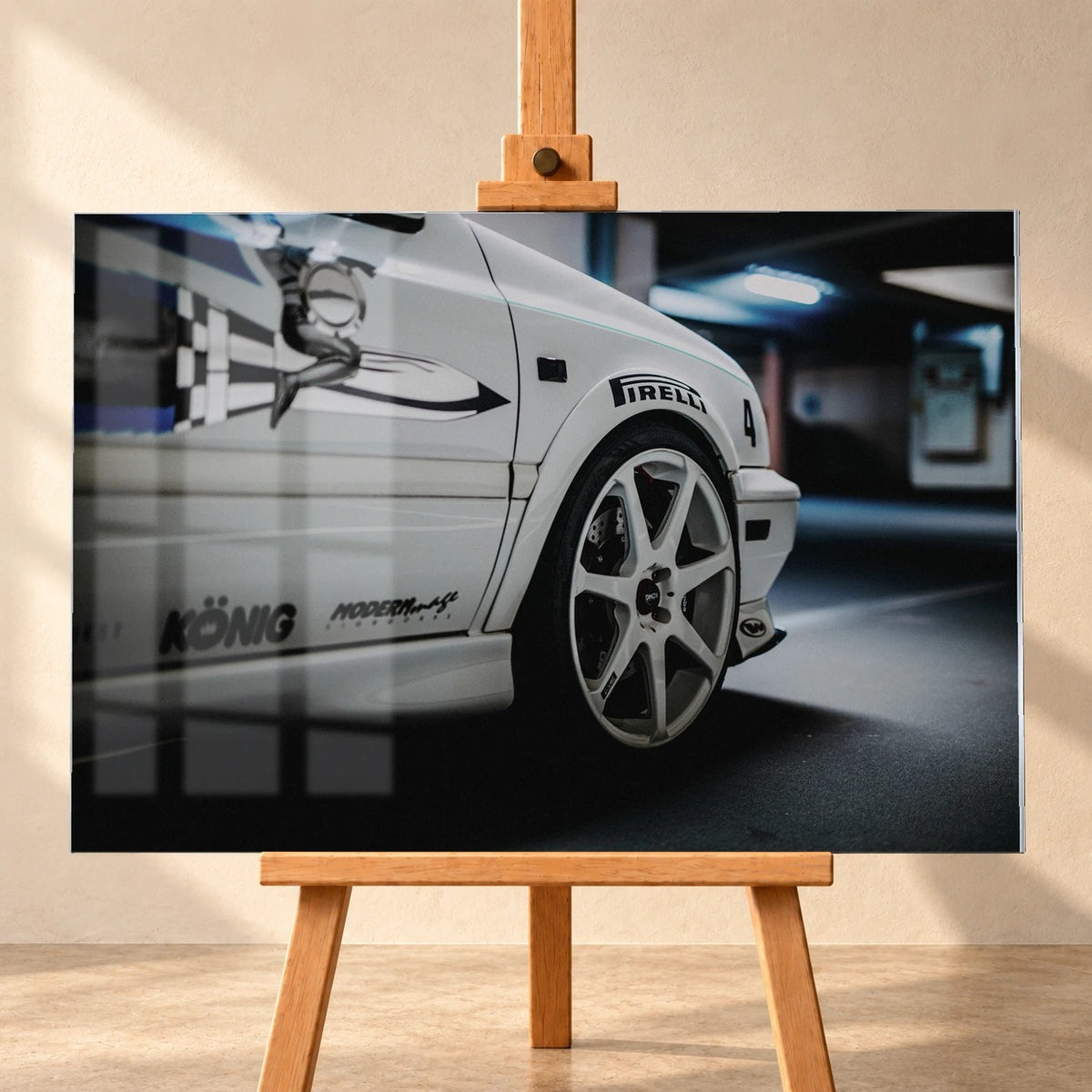 Frontal dargestelltes Acrylglas-Wandbild auf einer Holzstaffelei vor heller Wand, als Produktvisualisierung mit Fensterreflexionen auf der Bildfläche. Zu sehen ist die vordere Seitenpartie von Jesses weißem VW Jetta aus „The Fast and the Furious“, dessen helle Felge das Motiv prägt.