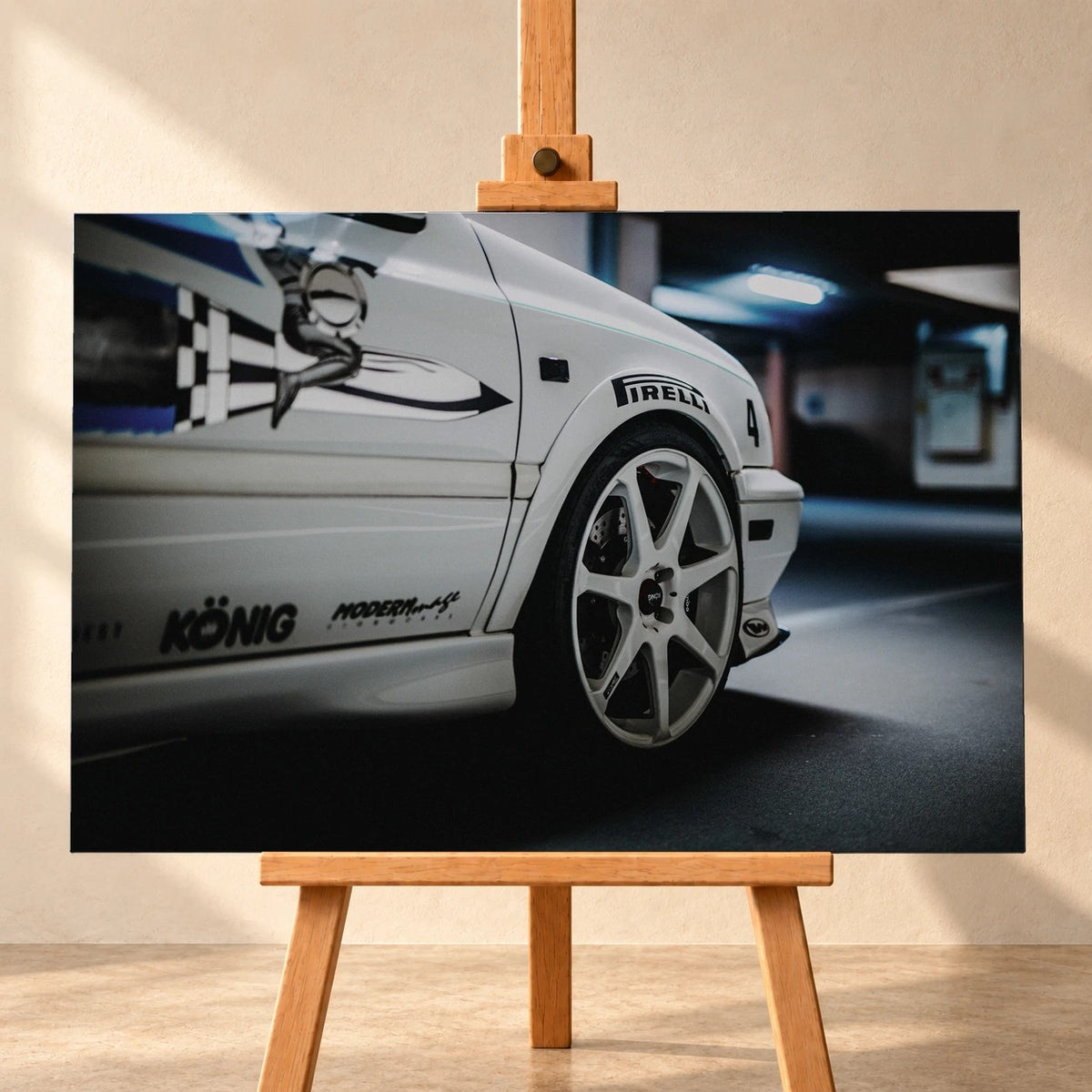 Visualisierung eines querformatigen Leinwandbilds auf einer Holzstaffelei vor heller Wand. Das Motiv zeigt die vordere Seitenpartie von Jesses weißem VW Jetta aus „The Fast and the Furious“, mit heller Mehrspeichenfelge und schwarz-blauer Seitengrafik.