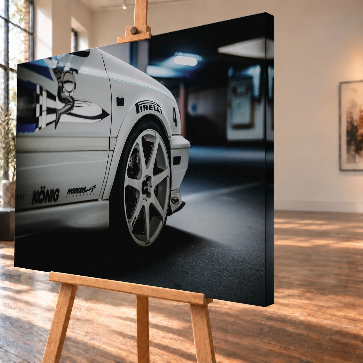 Schrägansicht eines visualisierten Leinwandbilds auf einer Holzstaffelei mit deutlich sichtbarer rechter Seitenkante. Das Motiv zeigt das Vorderrad des weißen VW Jetta aus „The Fast and the Furious“; am Kotflügel sind der Pirelli-Schriftzug und die Nummer 4 zu erkennen.