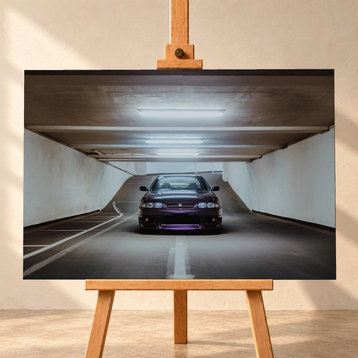 Frontale Visualisierung eines querformatigen Leinwandbildes auf einer Holzstaffelei vor einer hellen Wand. Das Motiv zeigt einen dunkelvioletten Nissan Skyline GT-R R33 mittig in einer Tiefgaragenzufahrt unter hellen Deckenleuchten.
