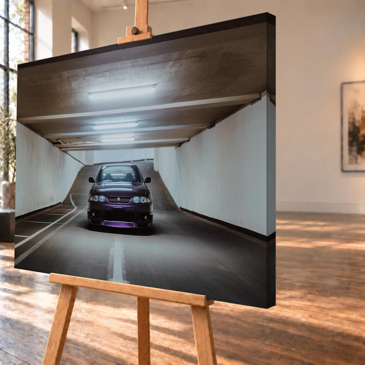 Produktvisualisierung des Leinwandbildes in schräger Ansicht auf einer Holzstaffelei, mit deutlich sichtbarer rechter Seitenkante. Auf dem Motiv steht ein dunkelvioletter Nissan Skyline GT-R R33 frontal zwischen den weißen Wänden einer Tiefgaragenzufahrt.