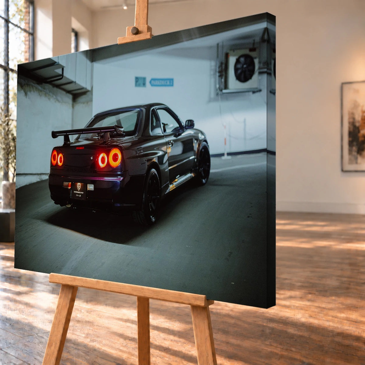 Schrägansicht eines als Leinwandbild visualisierten Nissan-Skyline-R34-Motivs auf einer Holzstaffelei. Die rechte Seitenkante des Bilds ist sichtbar; im Motiv stehen die vier roten Rücklichter und der Heckflügel des dunkelvioletten Wagens in der Tiefgarage im Vordergrund.