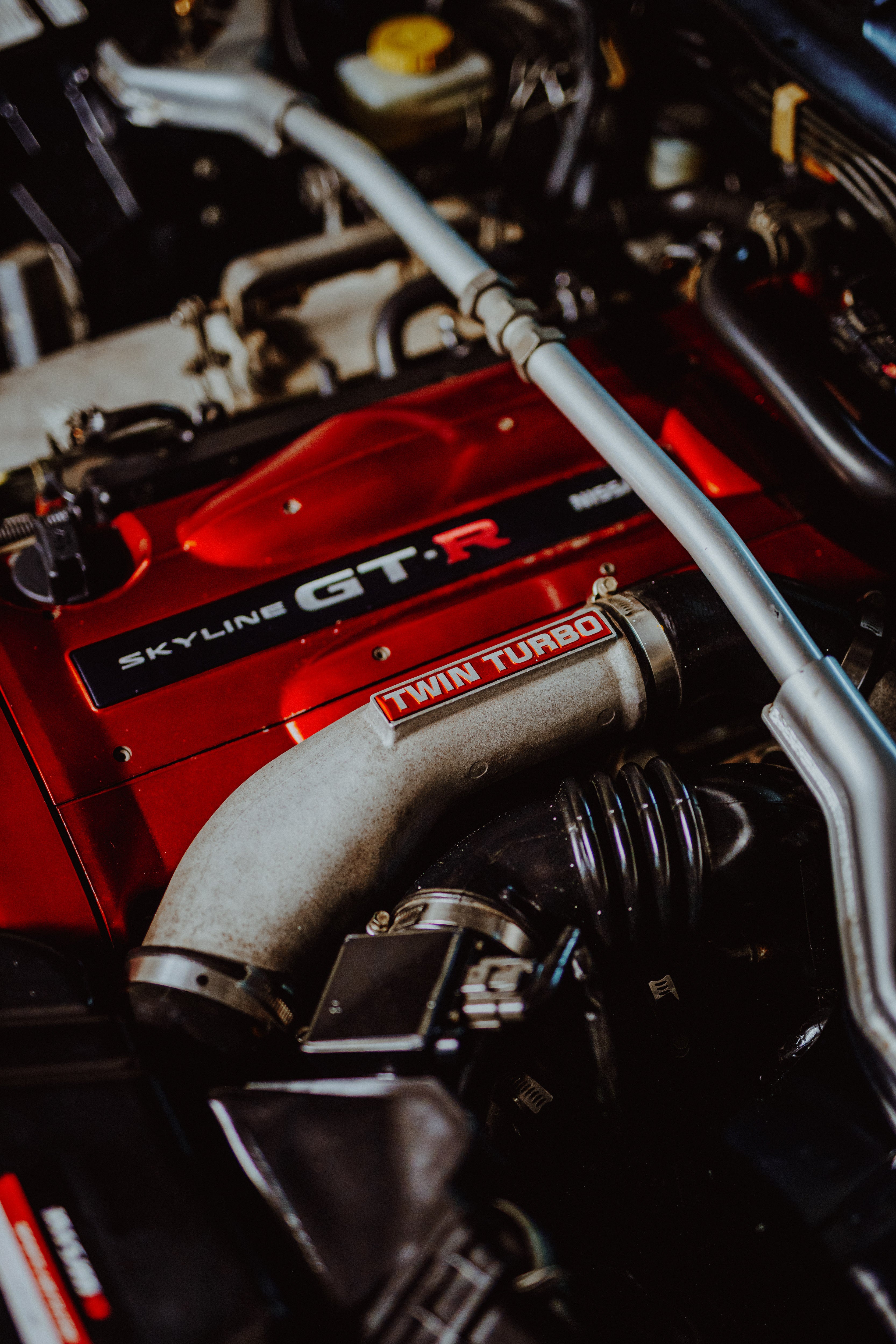 Motorraum mit rotem Nissan-Twin-Cam-Schriftzug, silbernem Rohr mit Twin-Turbo-Schriftzug und schwarzen Schläuchen.