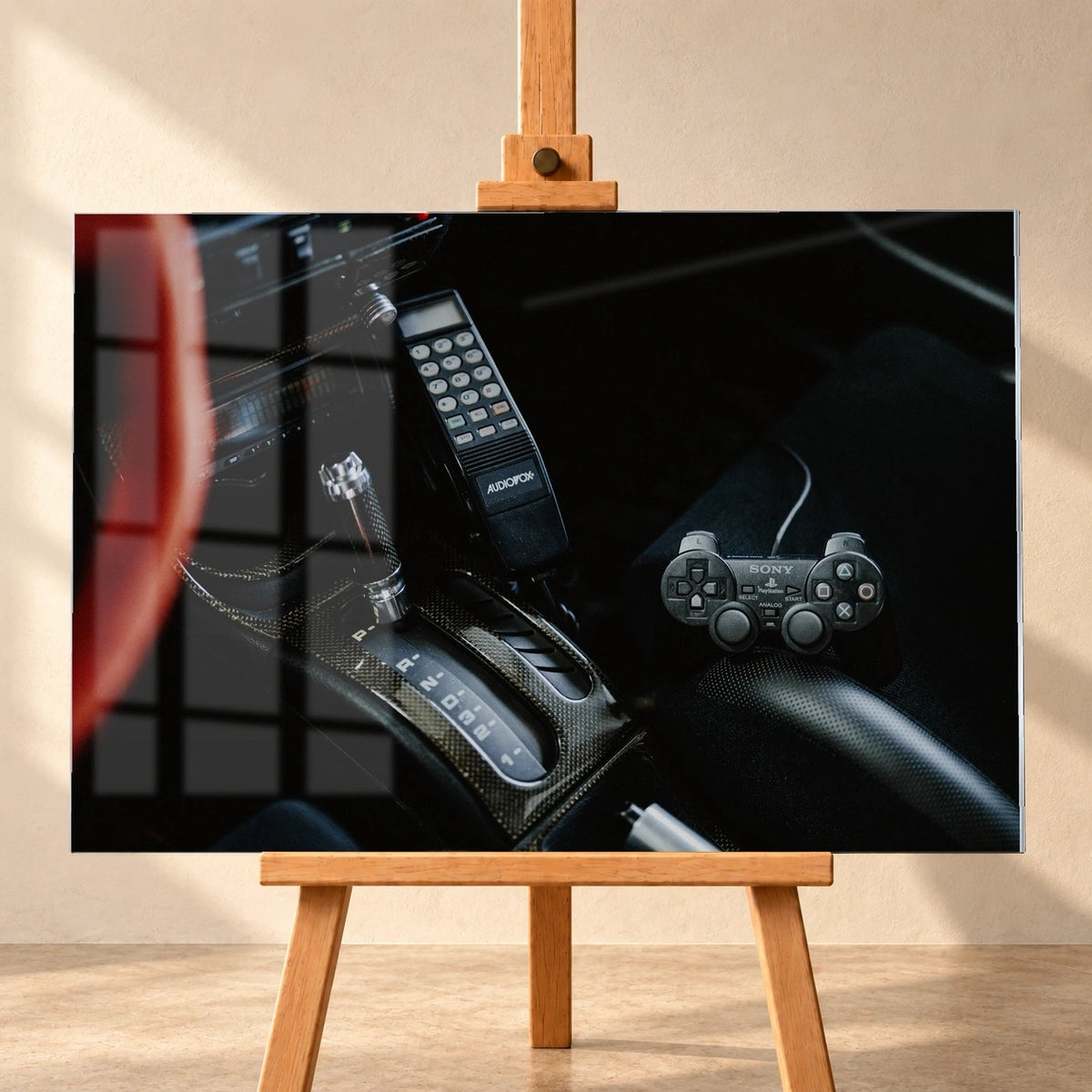 Die dunkle Cockpitaufnahme konzentriert sich auf Automatik-Wählhebel, Bedieneinheit und PlayStation-Controller. Motiv „Night Light“ als Acrylglas-Wandbild, frontal auf einer Holzstaffelei.