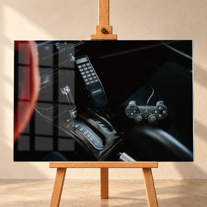 Die dunkle Cockpitaufnahme konzentriert sich auf Automatik-Wählhebel, Bedieneinheit und PlayStation-Controller. Motiv „Night Light“ als Acrylglas-Wandbild, frontal auf einer Holzstaffelei.