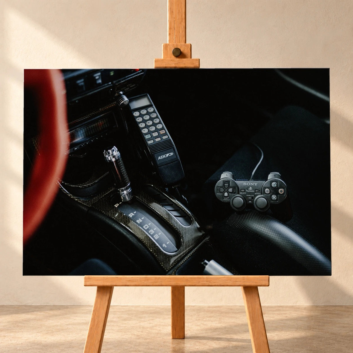 Die dunkle Cockpitaufnahme konzentriert sich auf Automatik-Wählhebel, Bedieneinheit und PlayStation-Controller. Motiv „Night Light“ als Leinwand-Wandbild, frontal auf einer Holzstaffelei.