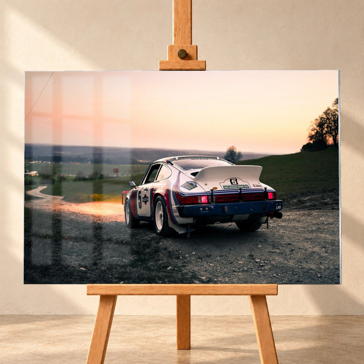Der Porsche 911 Safari steht von hinten auf einer Anhöhe im Abendrot; weiter Himmel und orangefarbene Horizontlinie öffnen das Bild. Motiv „Fast Motion“ als Acrylglas-Wandbild, frontal auf einer Holzstaffelei.
