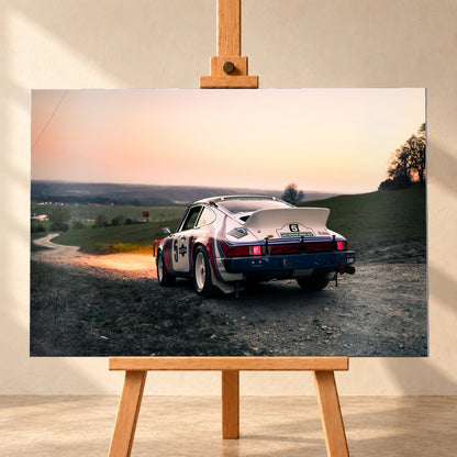 Der Porsche 911 Safari steht von hinten auf einer Anhöhe im Abendrot; weiter Himmel und orangefarbene Horizontlinie öffnen das Bild. Motiv „Fast Motion“ als Alu gebürstet-Wandbild, frontal auf einer Holzstaffelei.