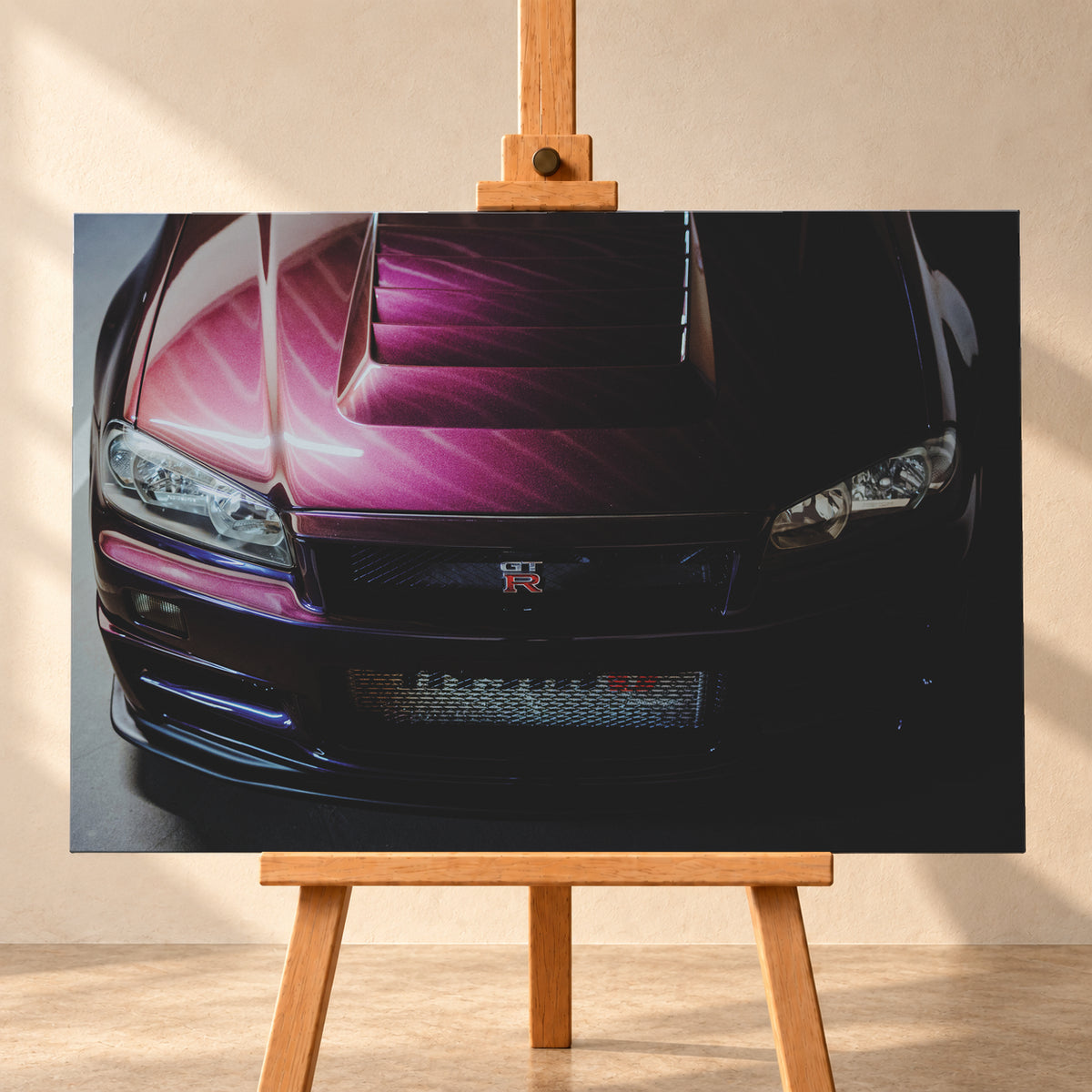 Enge Frontansicht eines dunkelvioletten Nissan Skyline R34 mit sichtbarem GT-R-Emblem, Haubenöffnungen und Scheinwerfern; magentafarbenes Licht links, tiefer Schatten rechts; Visualisierung als Leinwand-Wandbild, frontal auf einer Holzstaffelei.