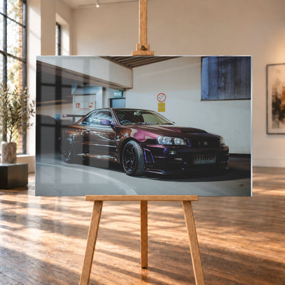 Dunkelvioletter Nissan Skyline R34 in einem Parkhaus, schräg von vorn fotografiert, mit schwarzen Rädern, großem Heckflügel und pink-violetten Lichtreflexionen auf der Karosserie; Visualisierung als Acrylglas-Wandbild, auf einer Holzstaffelei in einem hellen Galerieraum.