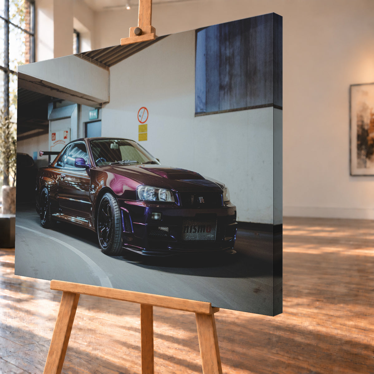 Dunkelvioletter Nissan Skyline R34 in einem Parkhaus, schräg von vorn fotografiert, mit schwarzen Rädern, großem Heckflügel und pink-violetten Lichtreflexionen auf der Karosserie; Visualisierung als Leinwand-Wandbild, schräg von der Seite auf einer Holzstaffelei.