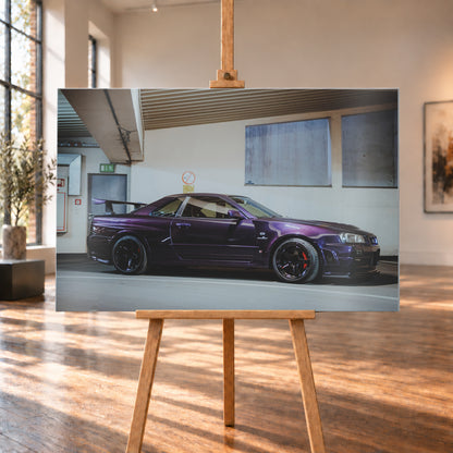 Violetter Nissan Skyline R34, nahezu seitlich mit der Front nach rechts, in einem hellen Parkgaragen-Innenraum; sichtbar sind schwarze Räder, rote Bremssättel und ein großer Heckflügel; Visualisierung als Alu gebürstet-Wandbild, auf einer Holzstaffelei in einem hellen Galerieraum.