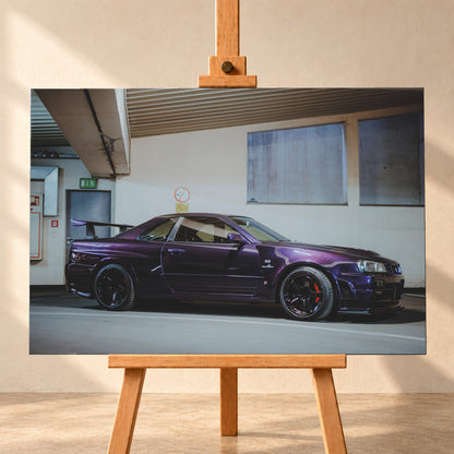 Violetter Nissan Skyline R34, nahezu seitlich mit der Front nach rechts, in einem hellen Parkgaragen-Innenraum; sichtbar sind schwarze Räder, rote Bremssättel und ein großer Heckflügel; Visualisierung als Leinwand-Wandbild, frontal auf einer Holzstaffelei.