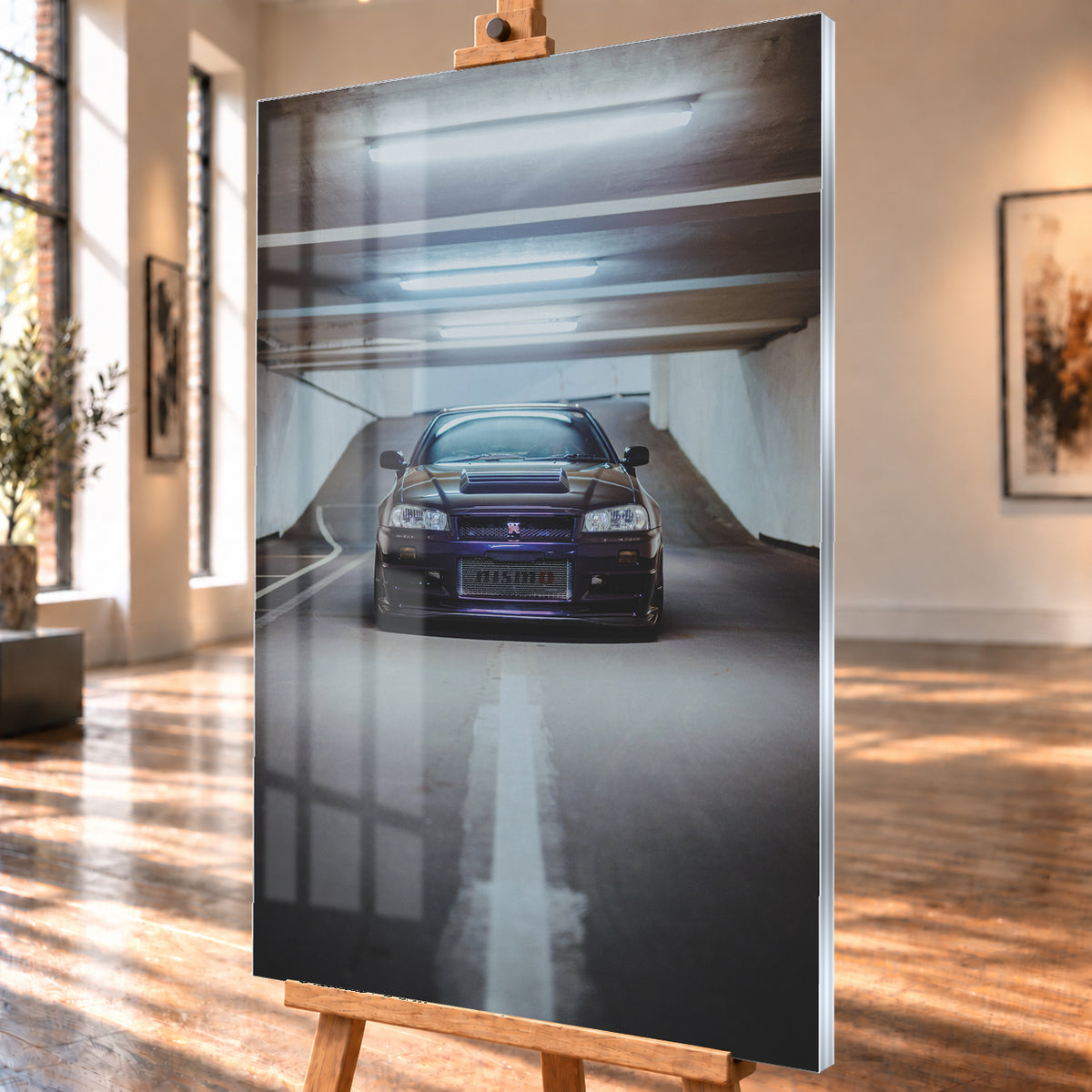 Dunkelvioletter Nissan Skyline R34 in zentraler Frontansicht auf der Zufahrt einer Parkgarage, beleuchtet von mehreren weißen Deckenleuchten und umgeben von grauen Wänden und Fahrbahnmarkierungen; Visualisierung als Acrylglas-Wandbild, schräg von der Seite auf einer Holzstaffelei.