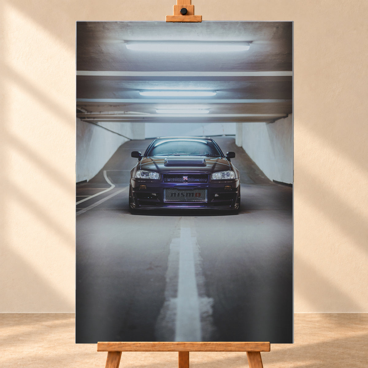Dunkelvioletter Nissan Skyline R34 in zentraler Frontansicht auf der Zufahrt einer Parkgarage, beleuchtet von mehreren weißen Deckenleuchten und umgeben von grauen Wänden und Fahrbahnmarkierungen; Visualisierung als Alu gebürstet-Wandbild, frontal auf einer Holzstaffelei.
