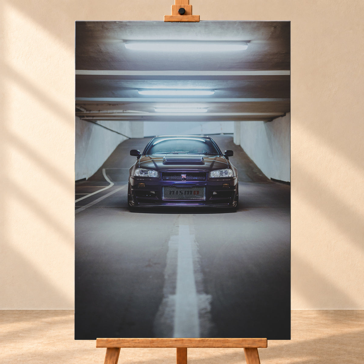Dunkelvioletter Nissan Skyline R34 in zentraler Frontansicht auf der Zufahrt einer Parkgarage, beleuchtet von mehreren weißen Deckenleuchten und umgeben von grauen Wänden und Fahrbahnmarkierungen; Visualisierung als Leinwand-Wandbild, frontal auf einer Holzstaffelei.