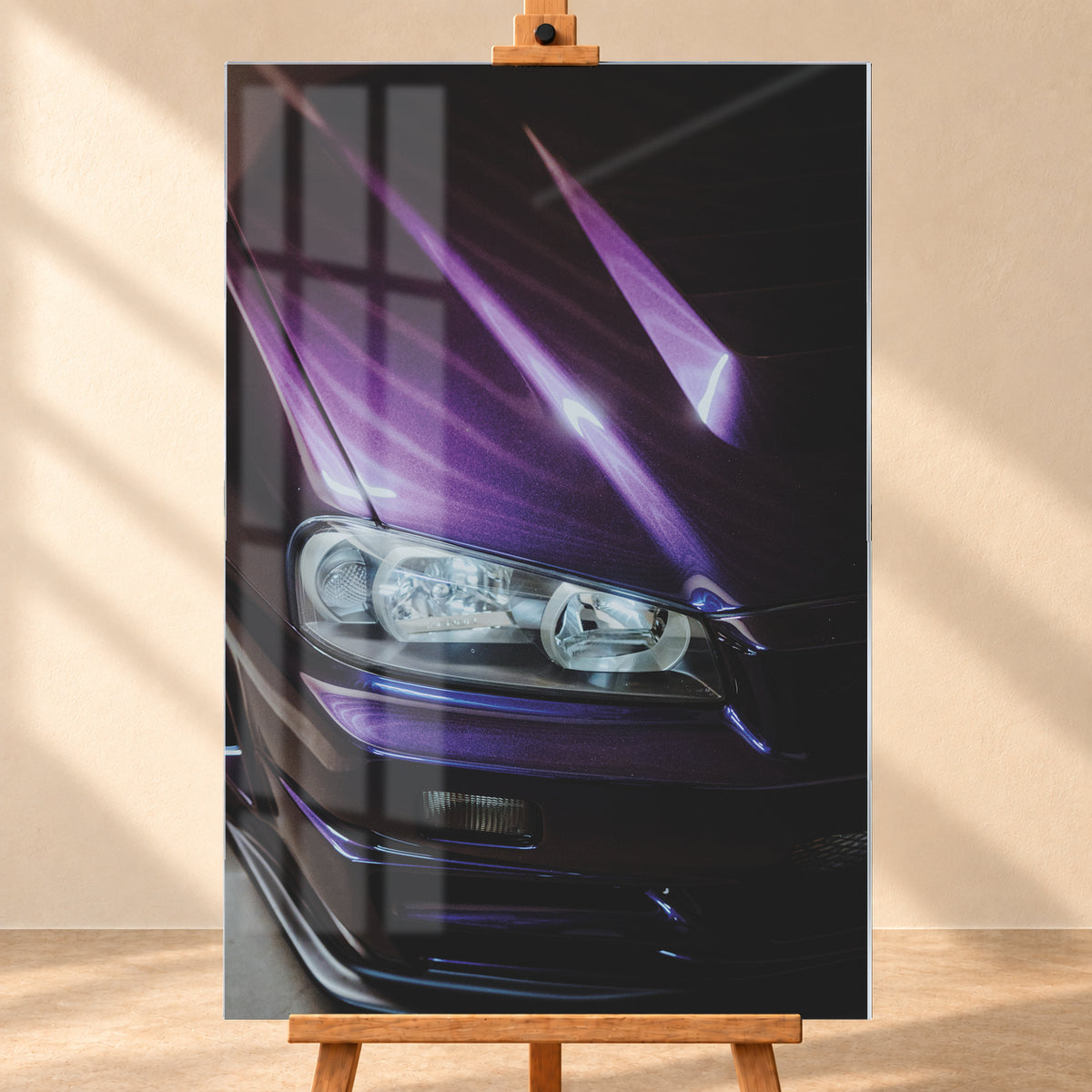 Nahaufnahme der dunkelvioletten Front eines Nissan Skyline R34, schräg von vorn fotografiert. Ein Scheinwerfer und Teile des Stoßfängers sind sichtbar; helle violette Reflexe verlaufen über die Motorhaube vor dunklem Hintergrund; Visualisierung als Acrylglas-Wandbild, frontal auf einer Holzstaffelei.