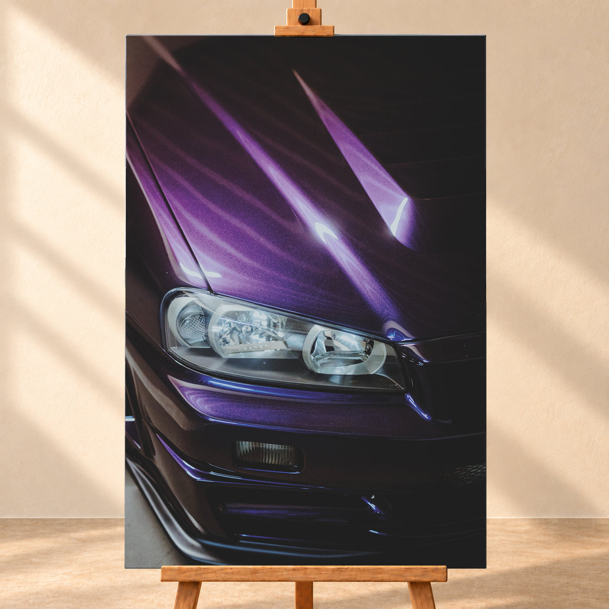 Nahaufnahme der dunkelvioletten Front eines Nissan Skyline R34, schräg von vorn fotografiert. Ein Scheinwerfer und Teile des Stoßfängers sind sichtbar; helle violette Reflexe verlaufen über die Motorhaube vor dunklem Hintergrund; Visualisierung als Leinwand-Wandbild, frontal auf einer Holzstaffelei.