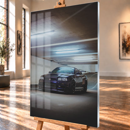 Dunkelvioletter Nissan Skyline R34 in Front-Dreiviertelansicht in einer Betonparkgarage. Kühle Deckenleuchten spiegeln sich auf der Karosserie; dunkle Räder, Seitenschweller und ein großer Heckflügel sind sichtbar. Das Hochformat zeigt viel dunkle Deckenfläche und eine ansteigende Rampe im Hintergrund; Visualisierung als Acrylglas-Wandbild, schräg von der Seite auf einer Holzstaffelei.