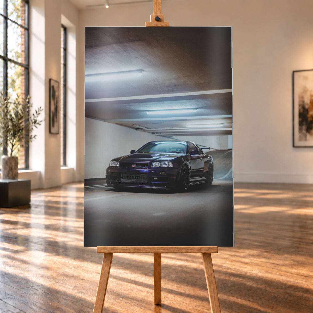 Dunkelvioletter Nissan Skyline R34 in Front-Dreiviertelansicht in einer Betonparkgarage. Kühle Deckenleuchten spiegeln sich auf der Karosserie; dunkle Räder, Seitenschweller und ein großer Heckflügel sind sichtbar. Das Hochformat zeigt viel dunkle Deckenfläche und eine ansteigende Rampe im Hintergrund; Visualisierung als Alu gebürstet-Wandbild, auf einer Holzstaffelei in einem hellen Galerieraum.