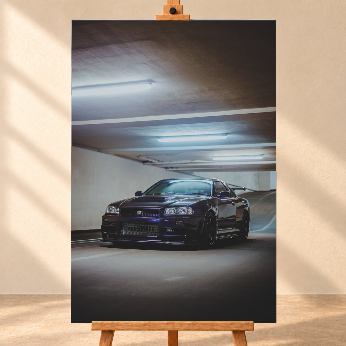 Dunkelvioletter Nissan Skyline R34 in Front-Dreiviertelansicht in einer Betonparkgarage. Kühle Deckenleuchten spiegeln sich auf der Karosserie; dunkle Räder, Seitenschweller und ein großer Heckflügel sind sichtbar. Das Hochformat zeigt viel dunkle Deckenfläche und eine ansteigende Rampe im Hintergrund; Visualisierung als Leinwand-Wandbild, frontal auf einer Holzstaffelei.
