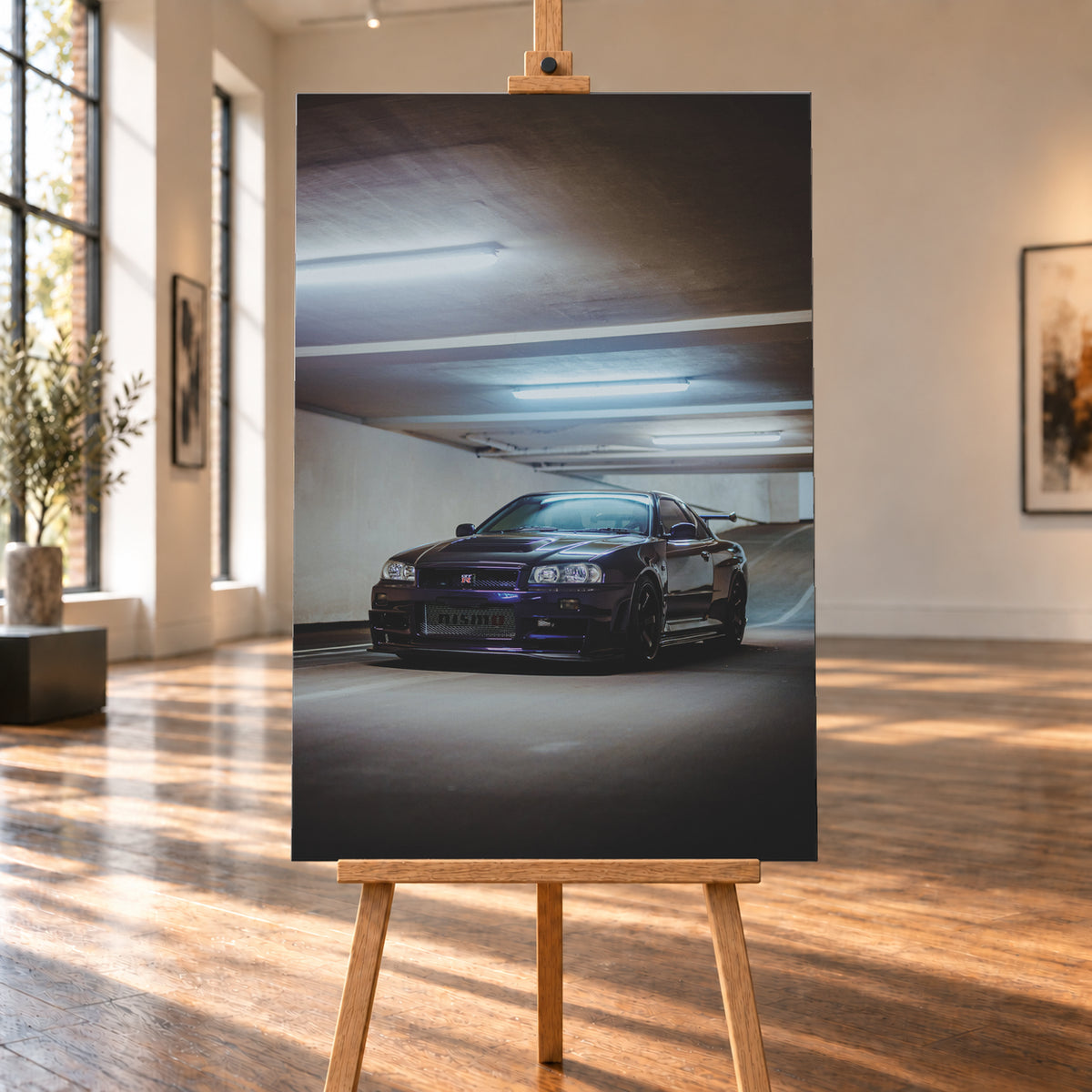 Dunkelvioletter Nissan Skyline R34 in Front-Dreiviertelansicht in einer Betonparkgarage. Kühle Deckenleuchten spiegeln sich auf der Karosserie; dunkle Räder, Seitenschweller und ein großer Heckflügel sind sichtbar. Das Hochformat zeigt viel dunkle Deckenfläche und eine ansteigende Rampe im Hintergrund; Visualisierung als Leinwand-Wandbild, auf einer Holzstaffelei in einem hellen Galerieraum.