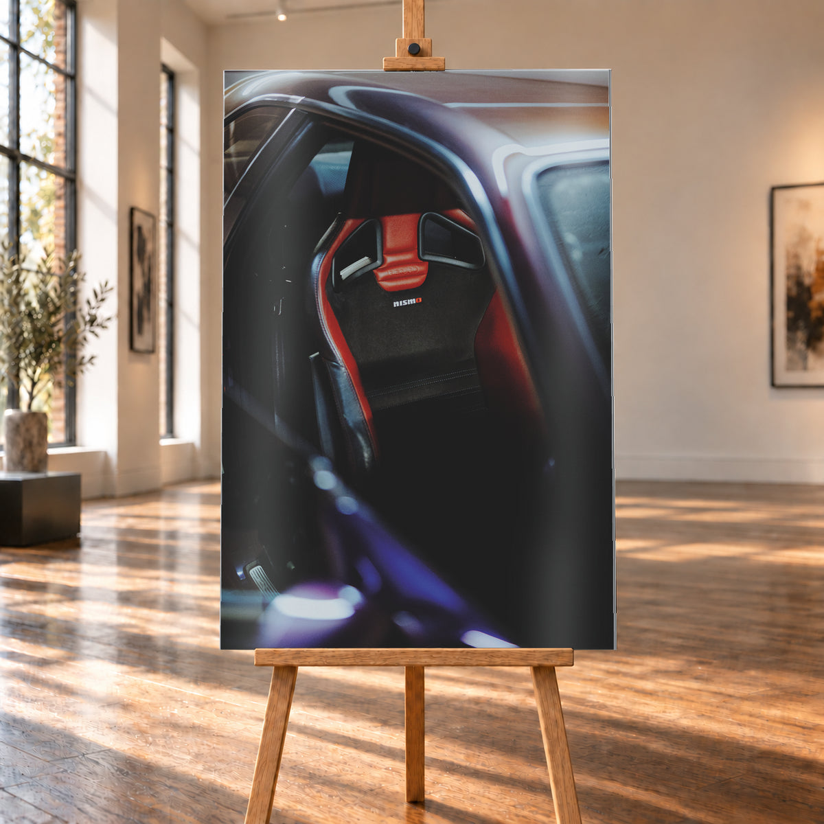 Nahaufnahme durch die geöffnete Tür eines violetten Nissan Skyline R34: Ein rot-schwarzer Sitz mit sichtbarem Nismo-Schriftzug steht im dunklen Innenraum; helle und blau-violette Reflexe verlaufen über Dachkante und Türrahmen; Visualisierung als Alu gebürstet-Wandbild, auf einer Holzstaffelei in einem hellen Galerieraum.