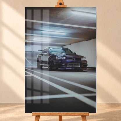 Dunkelvioletter Nissan Skyline R34 in niedriger Frontdreiviertelansicht in einer Beton-Parkgarage. Weiße Fahrbahnmarkierungen führen zum Fahrzeug; kühle Deckenleuchten spiegeln sich auf Haube und Scheibe. Sichtbar sind dunkle Räder und ein großer Heckflügel; Visualisierung als Acrylglas-Wandbild, frontal auf einer Holzstaffelei.