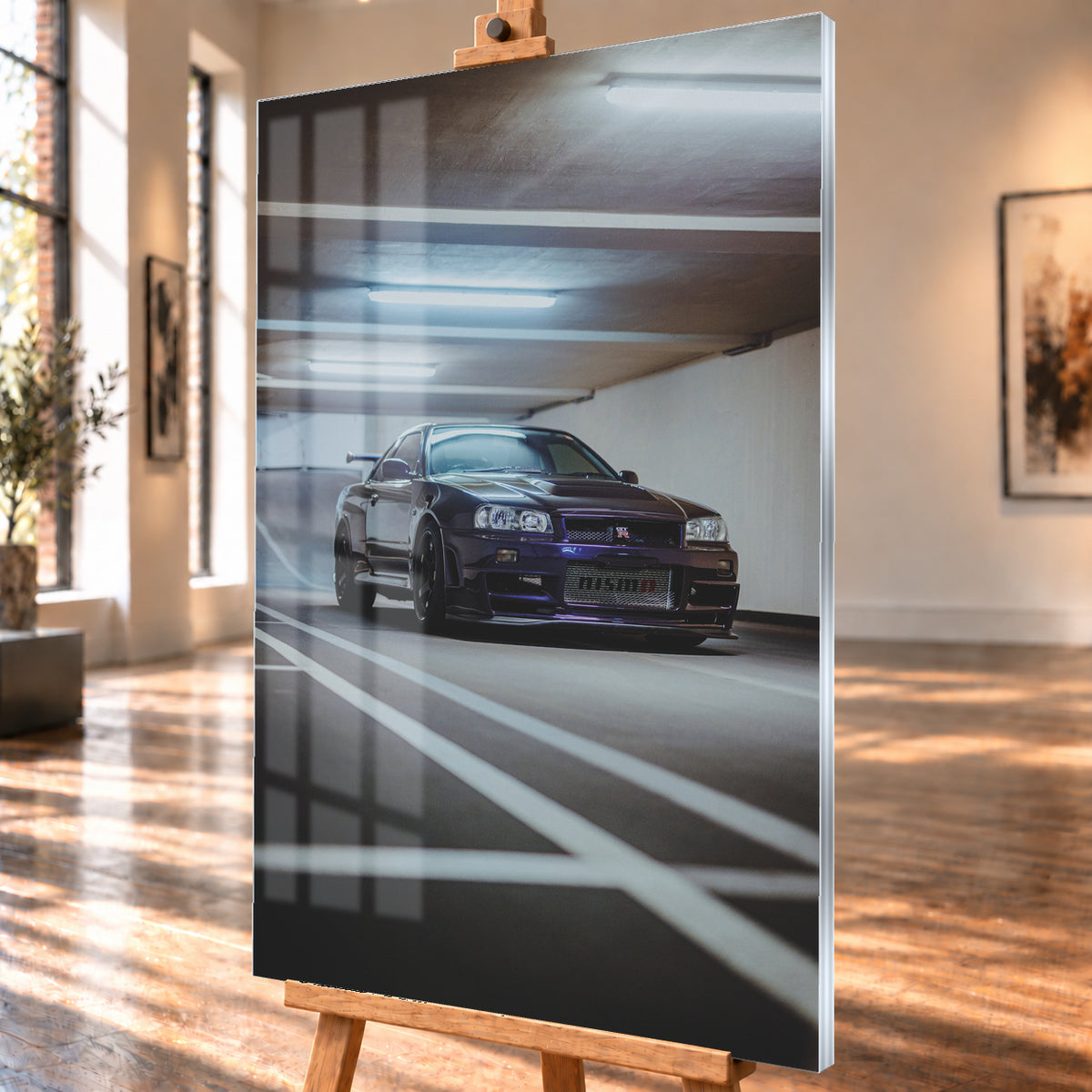 Dunkelvioletter Nissan Skyline R34 in niedriger Frontdreiviertelansicht in einer Beton-Parkgarage. Weiße Fahrbahnmarkierungen führen zum Fahrzeug; kühle Deckenleuchten spiegeln sich auf Haube und Scheibe. Sichtbar sind dunkle Räder und ein großer Heckflügel; Visualisierung als Acrylglas-Wandbild, schräg von der Seite auf einer Holzstaffelei.