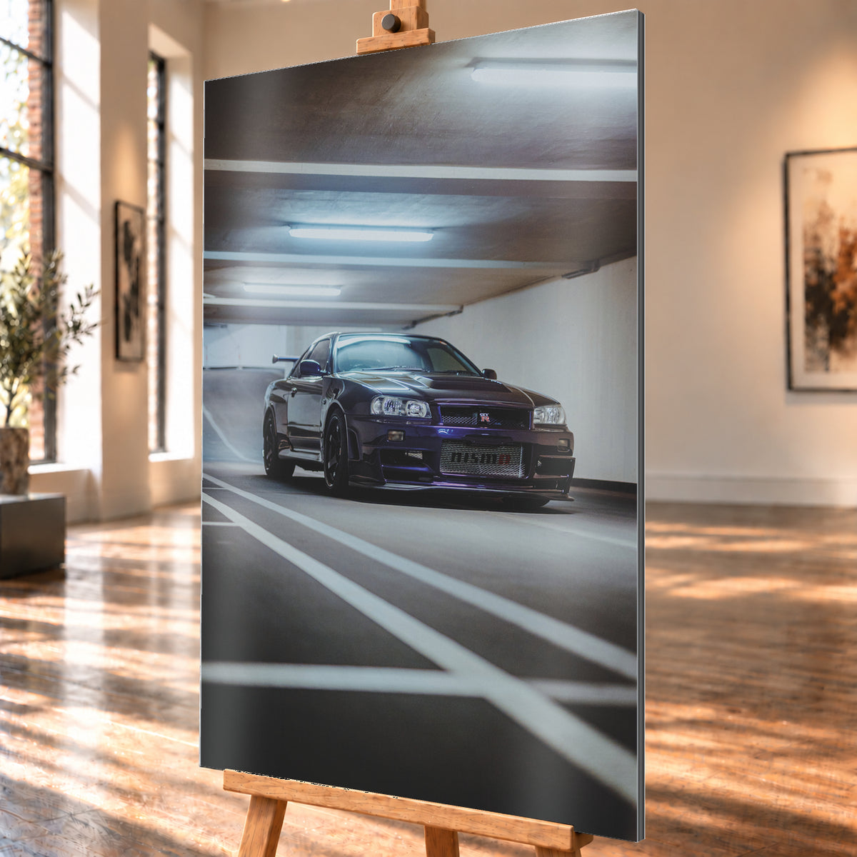 Dunkelvioletter Nissan Skyline R34 in niedriger Frontdreiviertelansicht in einer Beton-Parkgarage. Weiße Fahrbahnmarkierungen führen zum Fahrzeug; kühle Deckenleuchten spiegeln sich auf Haube und Scheibe. Sichtbar sind dunkle Räder und ein großer Heckflügel; Visualisierung als Alu gebürstet-Wandbild, schräg von der Seite auf einer Holzstaffelei.