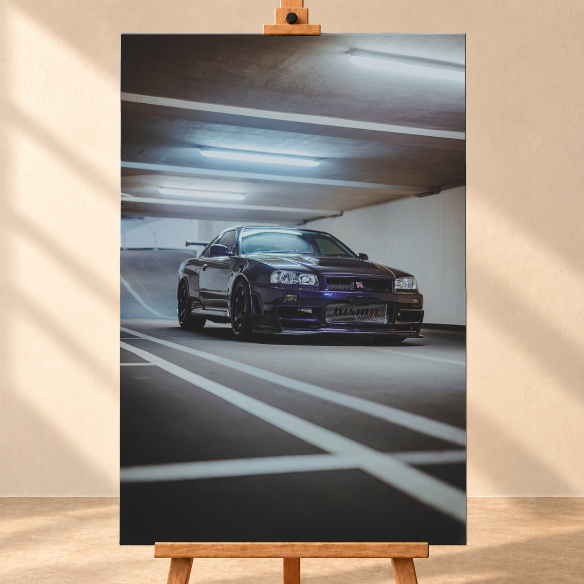 Dunkelvioletter Nissan Skyline R34 in niedriger Frontdreiviertelansicht in einer Beton-Parkgarage. Weiße Fahrbahnmarkierungen führen zum Fahrzeug; kühle Deckenleuchten spiegeln sich auf Haube und Scheibe. Sichtbar sind dunkle Räder und ein großer Heckflügel; Visualisierung als Leinwand-Wandbild, frontal auf einer Holzstaffelei.