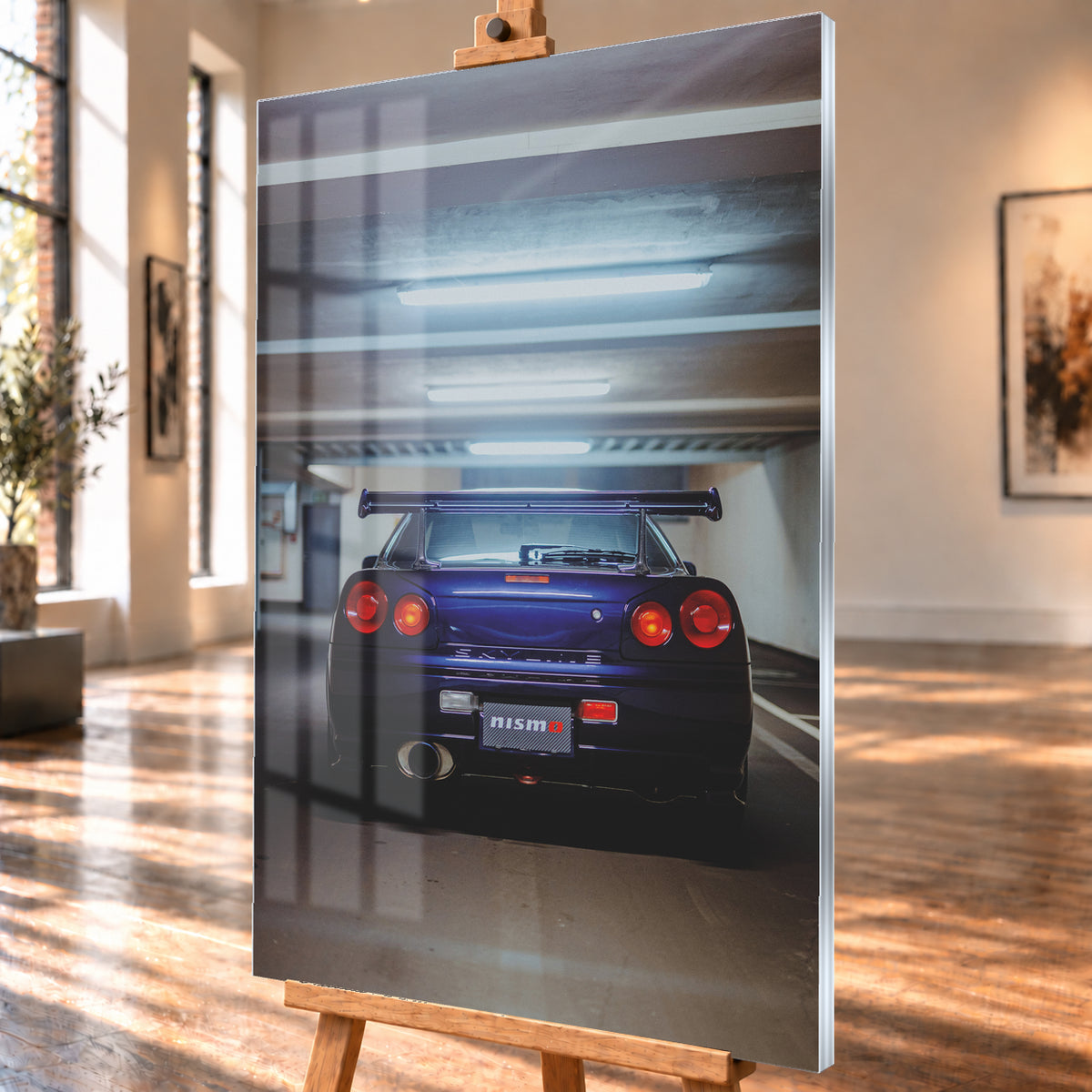Mittige Heckansicht eines dunkelvioletten Nissan Skyline R34 in einer Parkgarage. Vier runde rote Rückleuchten, davon die beiden inneren orange leuchtend, ein großer Heckflügel, ein rundes Auspuffendrohr und ein Nismo-Schriftzug sind unter kühlen, horizontalen Deckenleuchten zu sehen; Visualisierung als Acrylglas-Wandbild, schräg von der Seite auf einer Holzstaffelei.