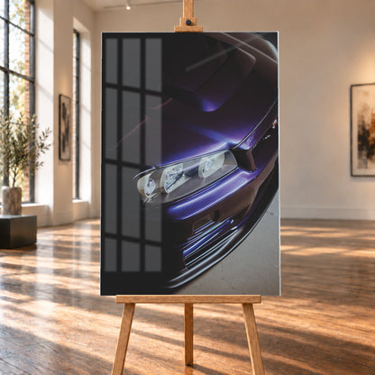 Steile Nahaufnahme der Front eines Nissan Skyline R34 in dunkelviolettem Lack mit Motorhaube, einem Scheinwerfer und Frontschürze; helle Reflexe zeichnen die Karosseriekanten vor einer überwiegend dunklen Umgebung nach; Visualisierung als Acrylglas-Wandbild, auf einer Holzstaffelei in einem hellen Galerieraum.