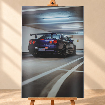 Dunkelvioletter Nissan Skyline R34 in tiefer Heck-Dreiviertelansicht in einer Beton-Parkgarage. Sichtbar sind vier rote Rundlichter, ein großer Heckflügel, dunkle Räder, ein großes Auspuffendrohr, weiße Fahrbahnlinien und kühle Deckenleuchten; Visualisierung als Alu gebürstet-Wandbild, frontal auf einer Holzstaffelei.