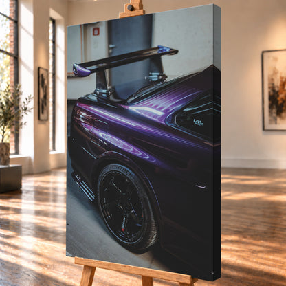 Nahaufnahme der hinteren Seitenpartie eines violetten Nissan Skyline R34 in einem Innenraum; sichtbar sind schwarzes Hinterrad, Radlauf, Heckscheibe und großer Heckflügel mit hellen Reflexionen; Visualisierung als Leinwand-Wandbild, schräg von der Seite auf einer Holzstaffelei.