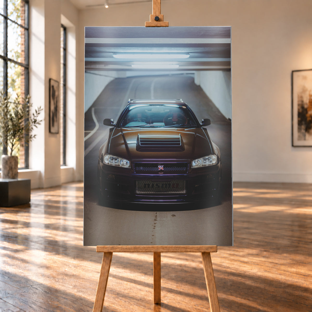 Frontale Ansicht eines dunkelvioletten Nissan Skyline R34 mit sichtbarem GT-R-Emblem in einer Tiefgarage, unter kühlen Deckenleuchten vor einer ansteigenden Fahrbahn; Visualisierung als Alu gebürstet-Wandbild, auf einer Holzstaffelei in einem hellen Galerieraum.