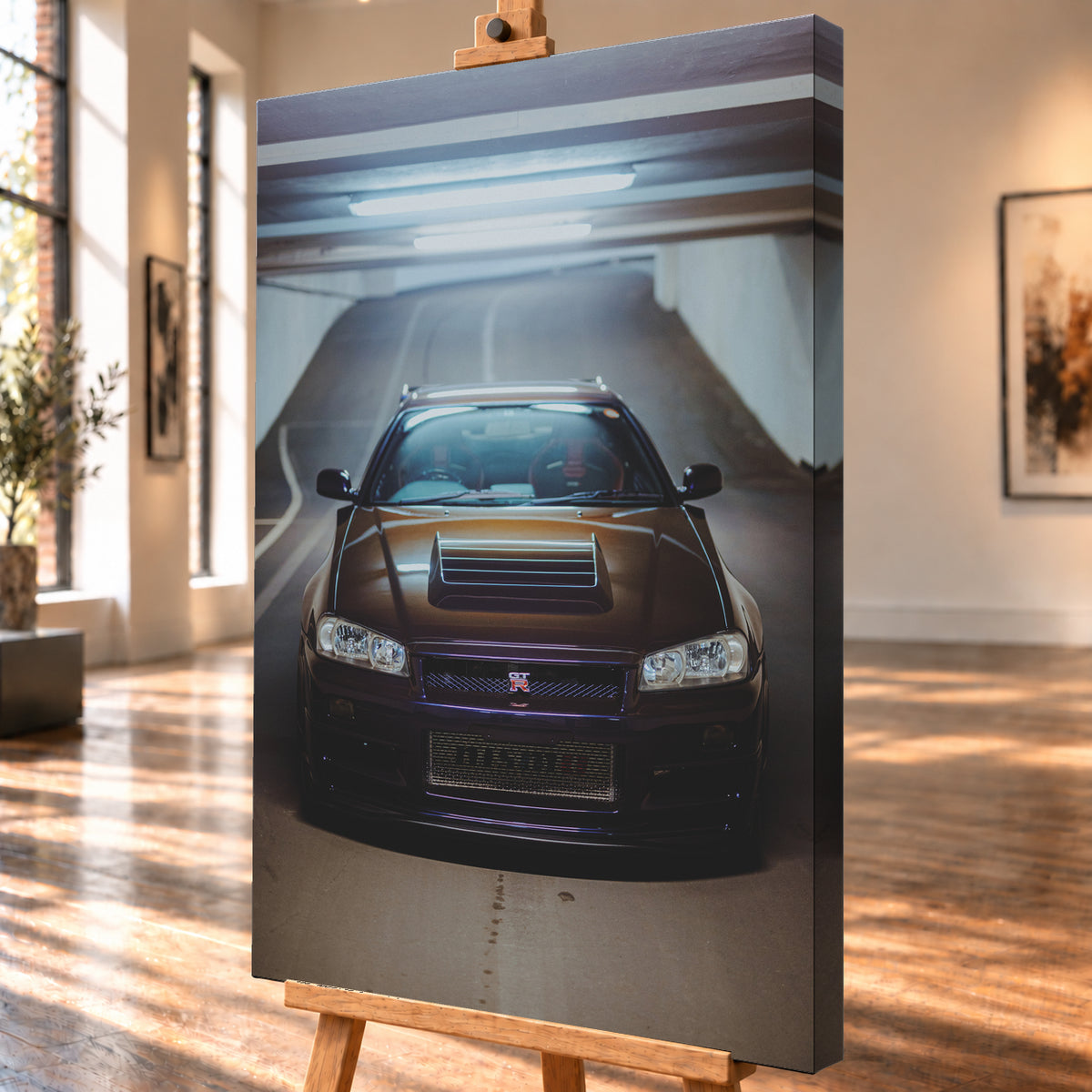 Frontale Ansicht eines dunkelvioletten Nissan Skyline R34 mit sichtbarem GT-R-Emblem in einer Tiefgarage, unter kühlen Deckenleuchten vor einer ansteigenden Fahrbahn; Visualisierung als Leinwand-Wandbild, schräg von der Seite auf einer Holzstaffelei.