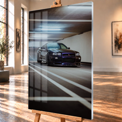 Dunkler Nissan Skyline R34 GT-R in niedriger Front-Dreiviertelansicht in einer Beton-Parkgarage, mit violett-blauen Reflexen, dunklen Rädern, Heckflügel, weißen Fahrbahnlinien und kühlen Deckenleuchten; Visualisierung als Acrylglas-Wandbild, schräg von der Seite auf einer Holzstaffelei.