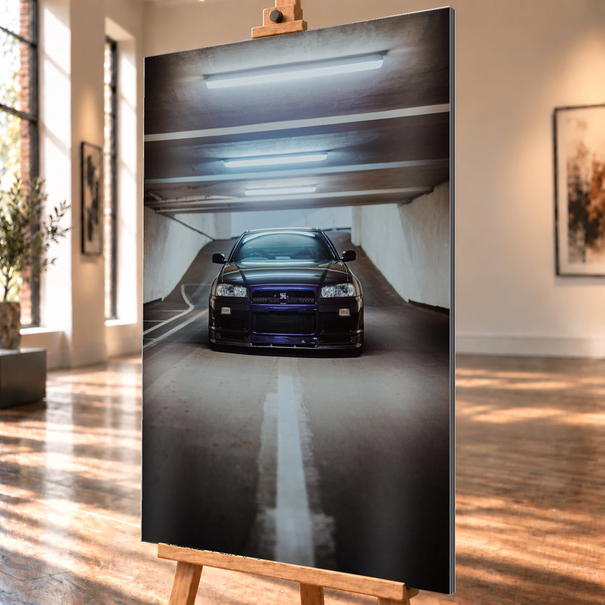 Dunkler Nissan Skyline R34 in frontaler Ansicht auf einer Betonrampe, unter kühlen weißen Deckenleuchten, mit mittiger Fahrbahnmarkierung und violettblauen Reflexen an Kühlergrill und Frontschürze; Visualisierung als Alu gebürstet-Wandbild, schräg von der Seite auf einer Holzstaffelei.