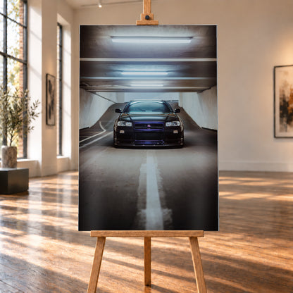 Dunkler Nissan Skyline R34 in frontaler Ansicht auf einer Betonrampe, unter kühlen weißen Deckenleuchten, mit mittiger Fahrbahnmarkierung und violettblauen Reflexen an Kühlergrill und Frontschürze; Visualisierung als Alu gebürstet-Wandbild, auf einer Holzstaffelei in einem hellen Galerieraum.