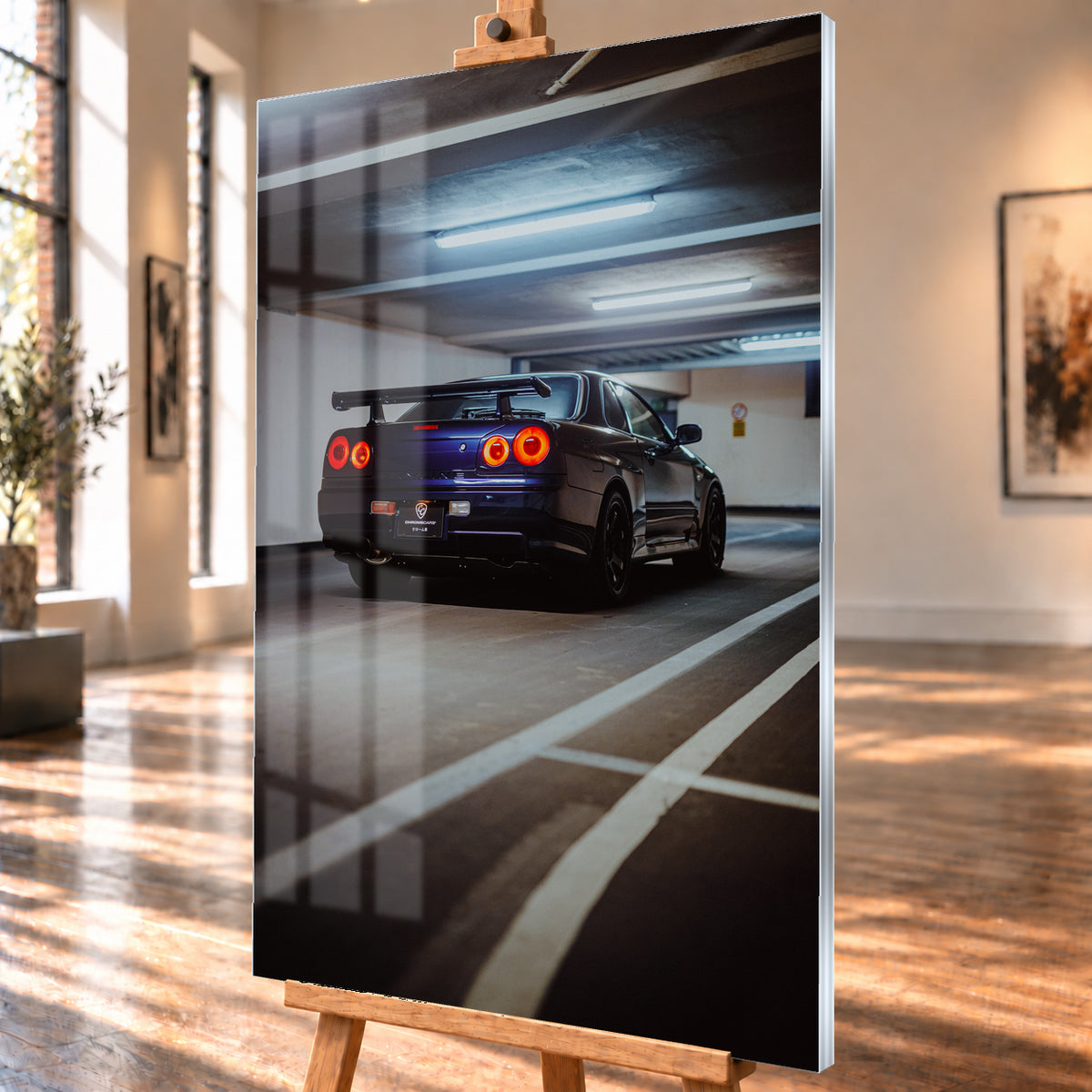 Dunkelblauer Nissan Skyline R34 in tiefer Dreiviertel-Heckansicht in einer Parkgarage; vier rote Rundrücklichter leuchten unter kühlen Deckenlampen, weiße Bodenlinien führen durch das Hochformat; Visualisierung als Acrylglas-Wandbild, schräg von der Seite auf einer Holzstaffelei.